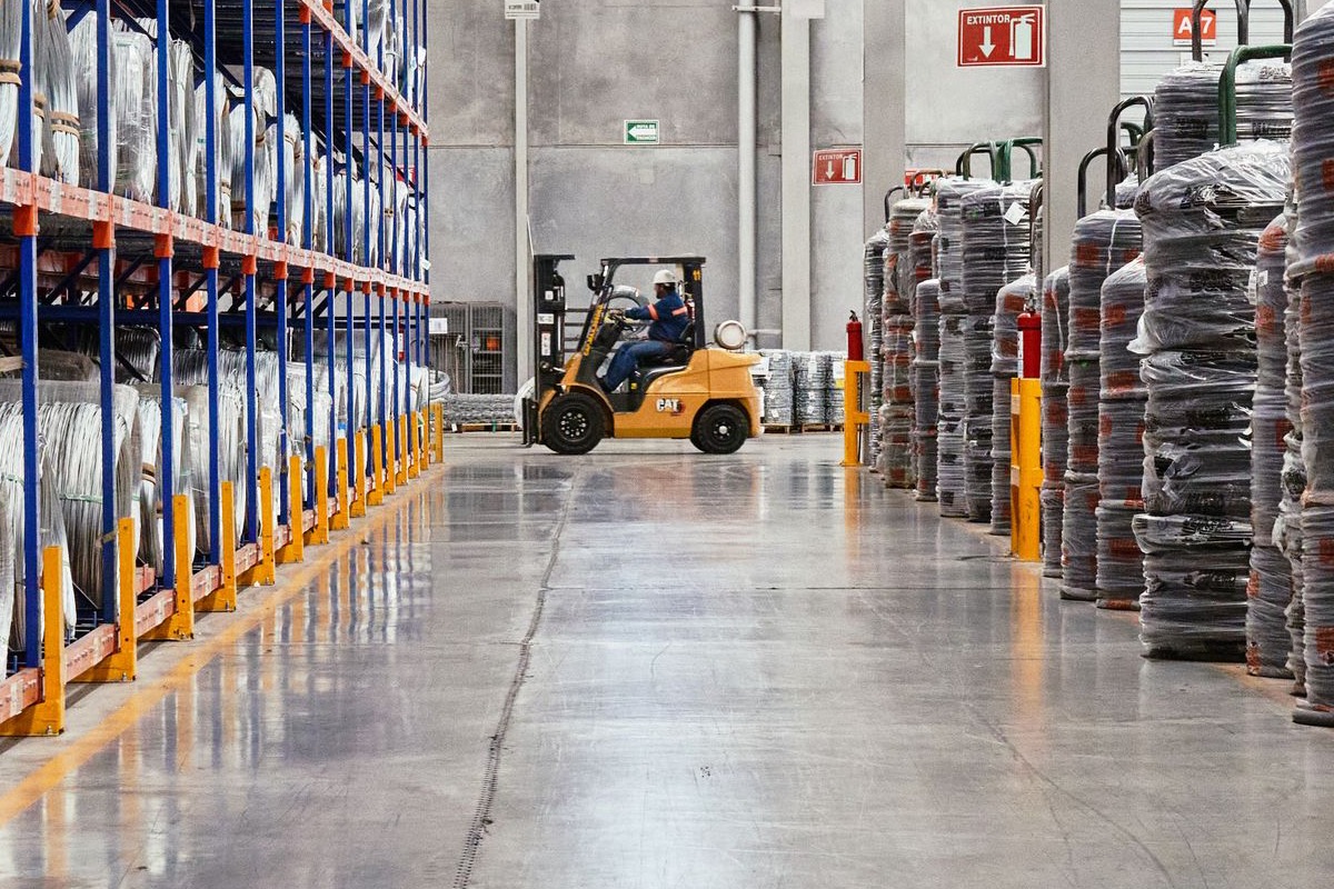 Forklift operating on a concrete warehouse floor beside storage racking